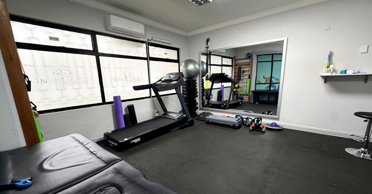 Sala de kinesiología de QuiroHome Chillán con trotadora, mancuernas, balón, bandas de suspensión y colchonetas