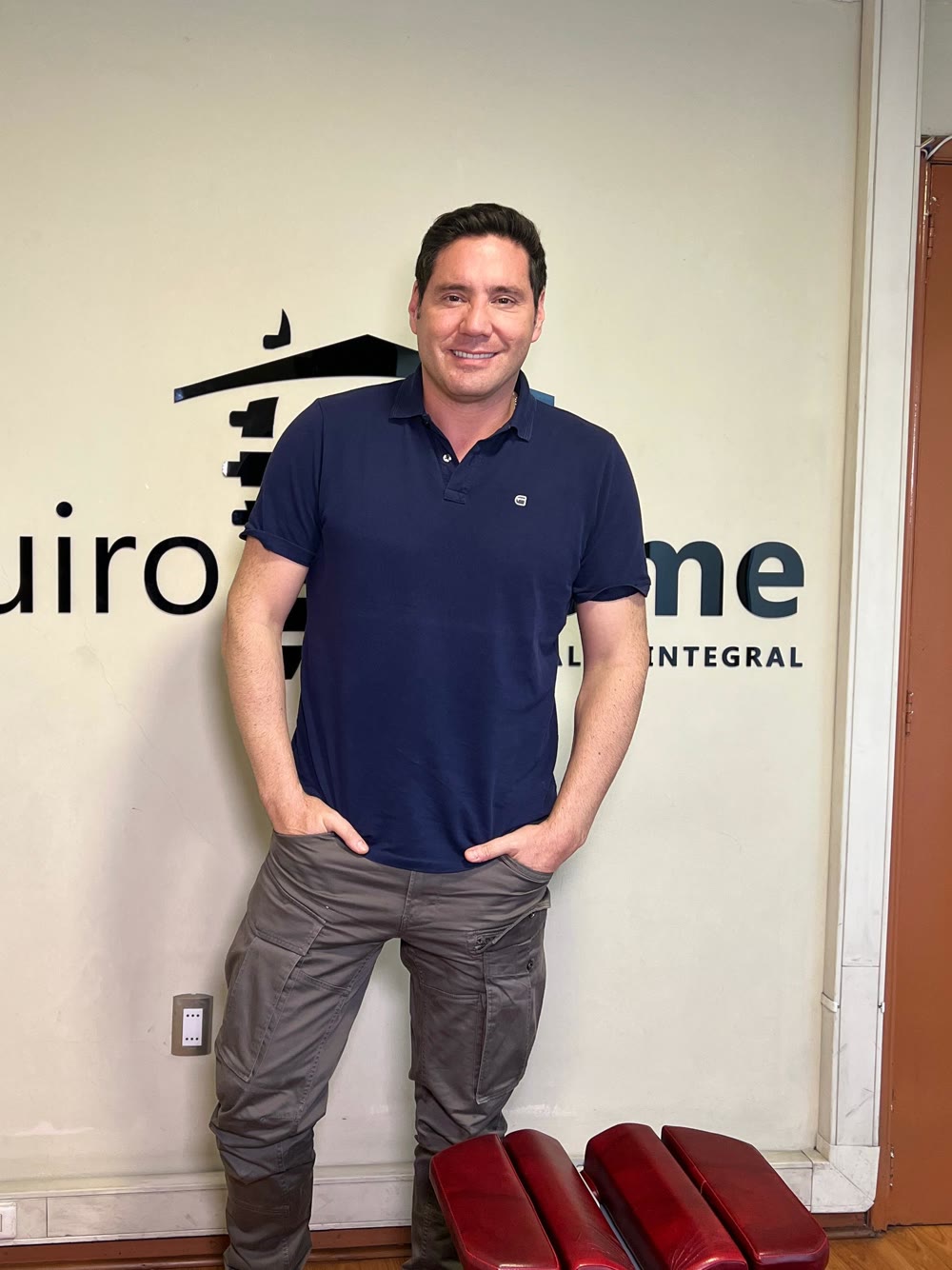 El animador Pancho Saavedra de pie frente al logo de QuiroHome