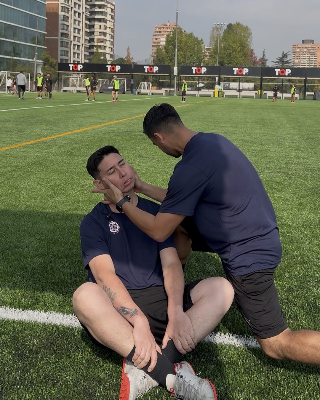 Evaluación de un futbolista sentado en el pasto, con el DC. Raúl Mancilla